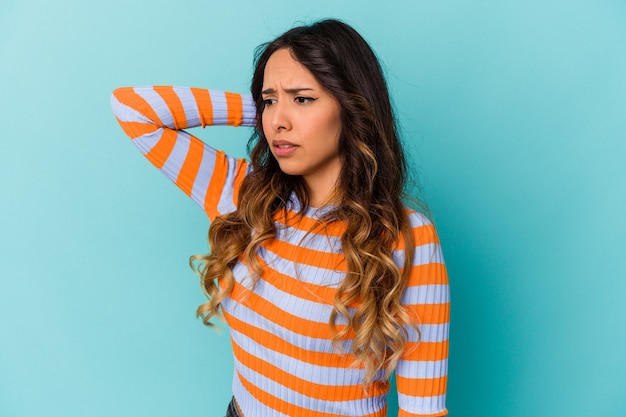 Jeune femme mexicaine isolée sur un mur bleu fatigué et très endormi en gardant la main sur la tête.