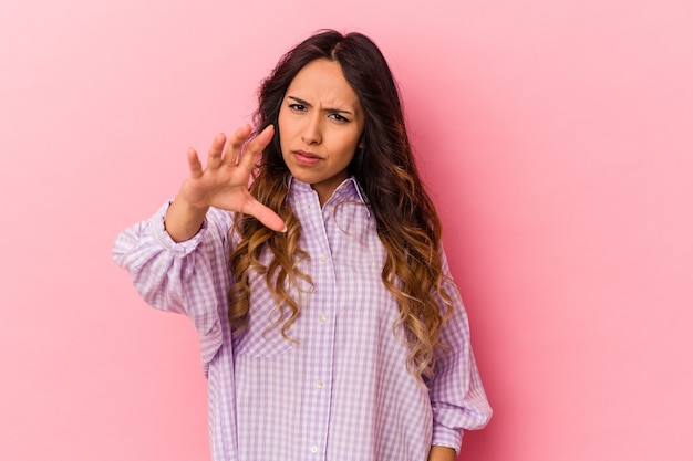 Jeune femme mexicaine isolée sur un mur rose montrant des griffes imitant un chat, geste agressif.