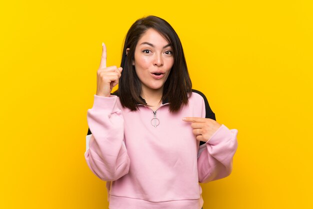 Jeune femme mexicaine sur jaune isolé avec une expression faciale surprise