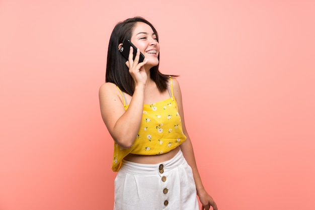 Jeune femme mexicaine sur un mur isolé, gardant une conversation avec le téléphone portable