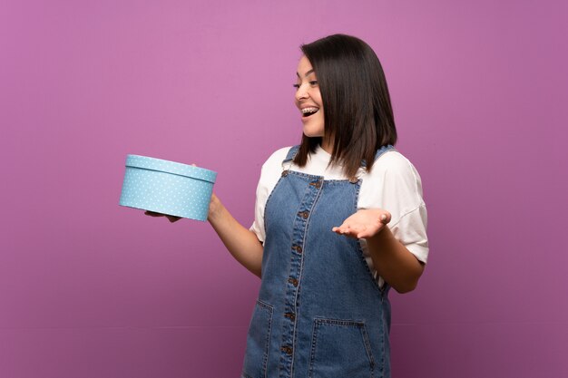 Jeune femme mexicaine sur mur isolé tenant une boîte-cadeau