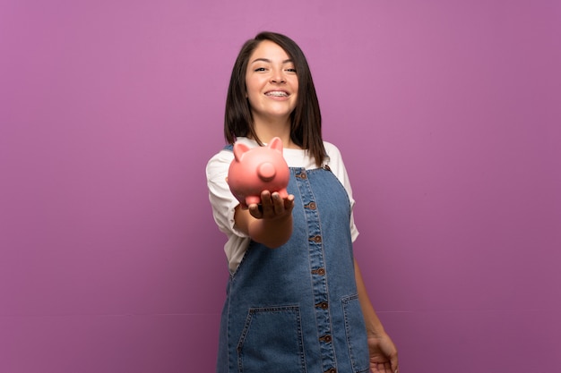 Jeune femme mexicaine sur mur isolé tenant une grande tirelire