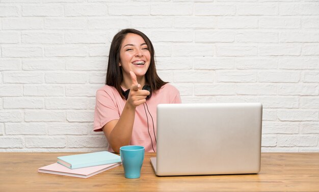 Jeune femme mexicaine avec un ordinateur portable pointe le doigt vers vous