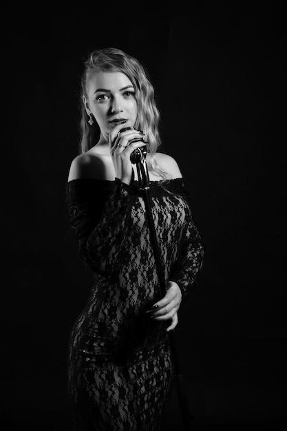 Jeune femme avec un microphone sur un fond sombre Photo noir et blanc