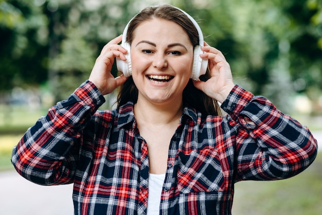 Jeune, femme, mignon, sourire, Porter, écouteurs, contre, ville