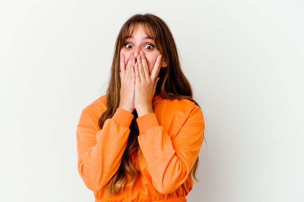 Photo jeune femme mignonne caucasienne isolée sur fond blanc choqué, couvrant la bouche avec les mains, impatiente de découvrir quelque chose de nouveau.