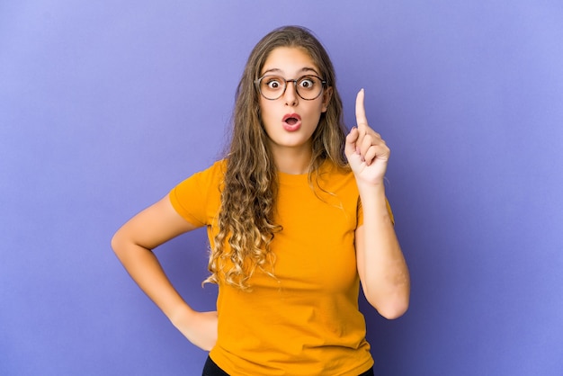 Jeune femme mignonne caucasienne pointant vers le haut avec la bouche ouverte.