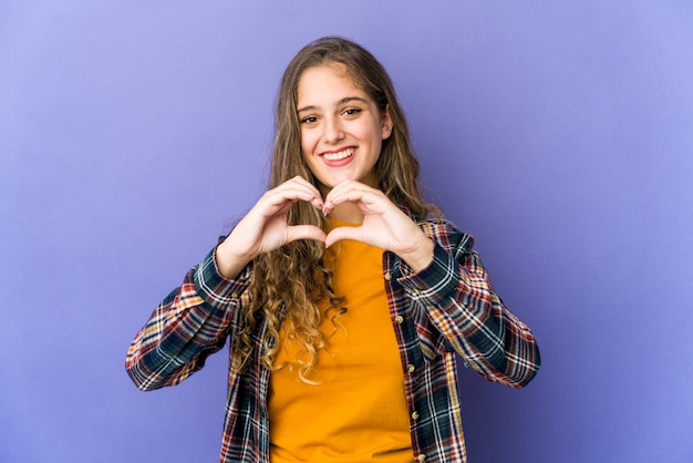 Jeune femme mignonne caucasienne souriante et montrant une forme de coeur avec les mains.