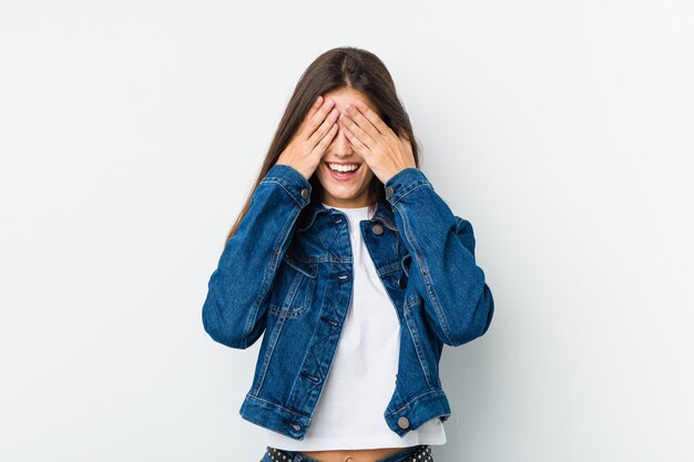 Jeune femme mignonne couvre les yeux avec les mains, sourit largement attend une surprise.