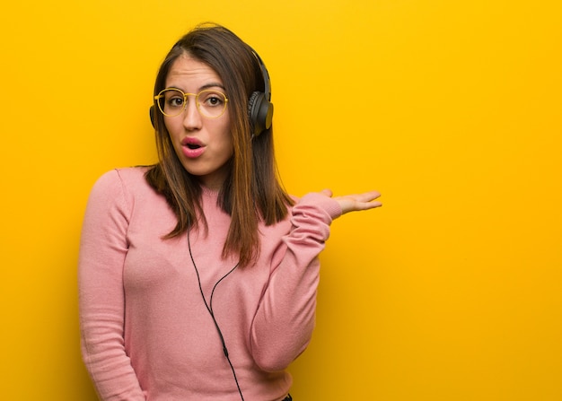 Jeune femme mignonne, écouter de la musique tenant quelque chose sur la main de la paume