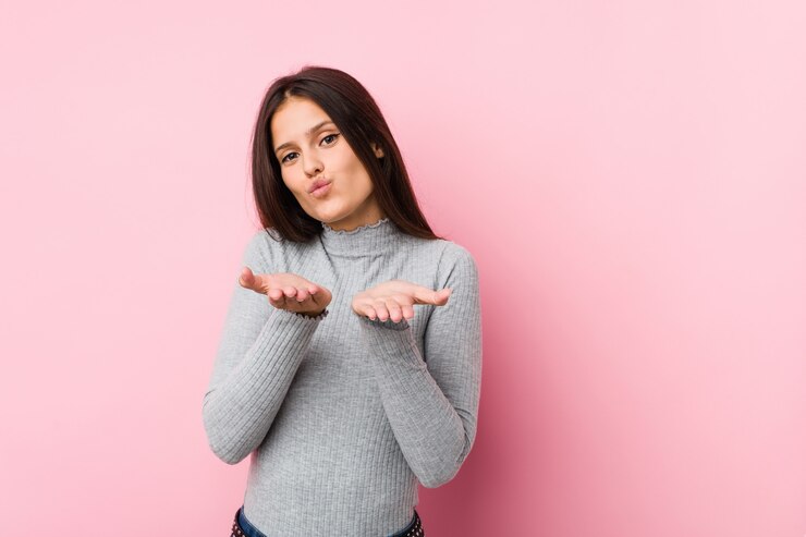 Photo jeune femme mignonne pliant les lèvres et tenant les paumes pour envoyer un baiser aérien