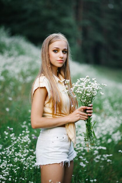 La jeune femme mignonne rassemble les fleurs sauvages blanches