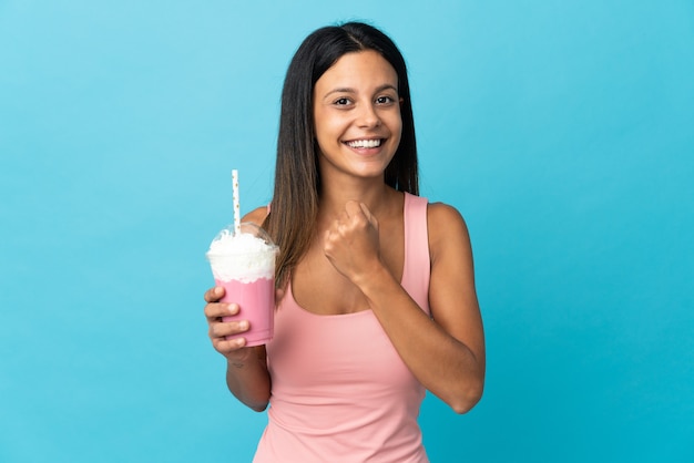 Jeune femme avec milk-shake aux fraises célébrant une victoire