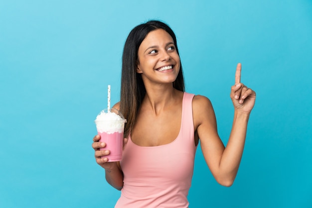 Jeune femme avec milkshake aux fraises pointant vers le haut une excellente idée