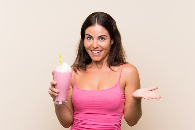 Jeune femme avec un milkshake à la fraise avec une expression faciale choquée