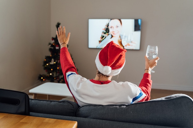 Jeune femme millénaire à l'aide de téléphone à la maison la veille de Noël. Achats de vacances en ligne, quarantaine