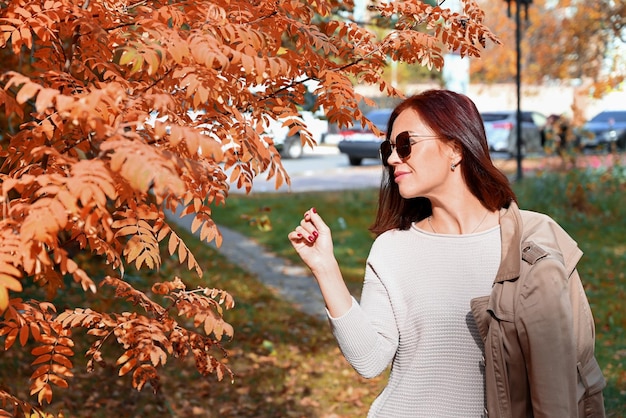 une jeune femme mince confiante dans un imperméable et des chaussures à talons hauts parle au téléphone dans une ville d'automne une femme sourit et profite de la vie