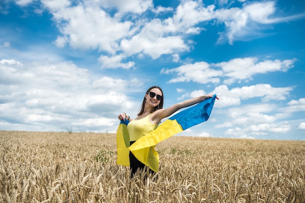 Jeune femme mince dans le drapeau bleu-jaune de l'Ukraine sur le champ de blé en été