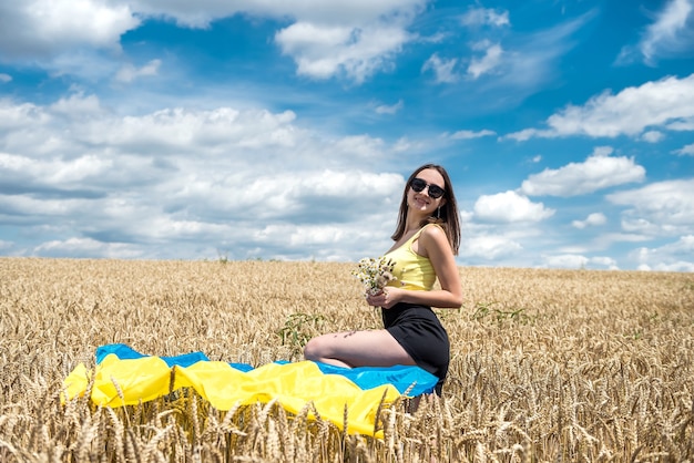 Jeune femme mince dans le drapeau bleu-jaune de l'Ukraine sur le champ de blé en été