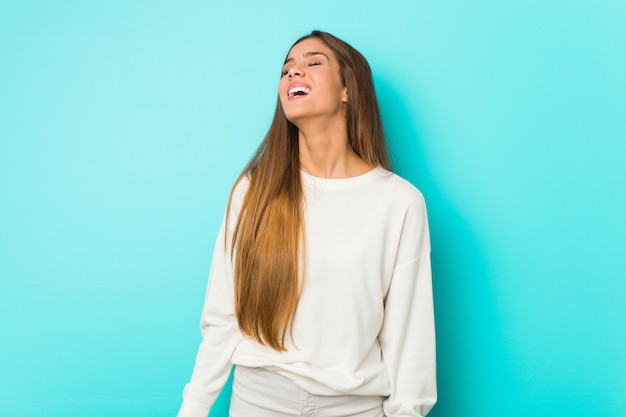 Jeune femme mince détendue et heureuse de rire, le cou tendu montrant les dents.