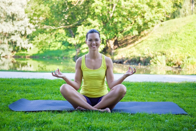 Jeune femme mince faisant des exercices de yoga dans le parc