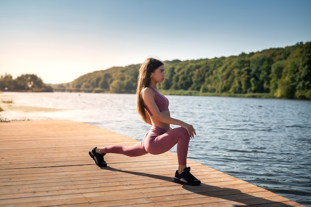 Une jeune femme mince fait des exercices de relaxation près du lac. concept de mode de vie sain