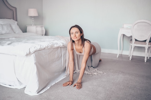 Jeune femme mince fit sportive faisant des exercices de yoga d'entraînement du matin dans la chambre à la quarantaine d'isolement.