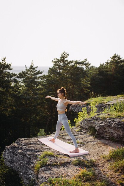 Photo une jeune femme mince pratiquant le yoga au coucher du soleil dans les montagnes