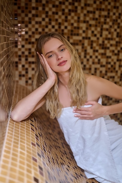 Une jeune femme mince avec une serviette blanche dans le sauna