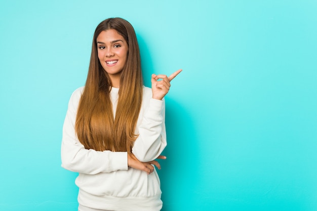 Jeune femme mince souriant joyeusement pointant avec l'index loin.