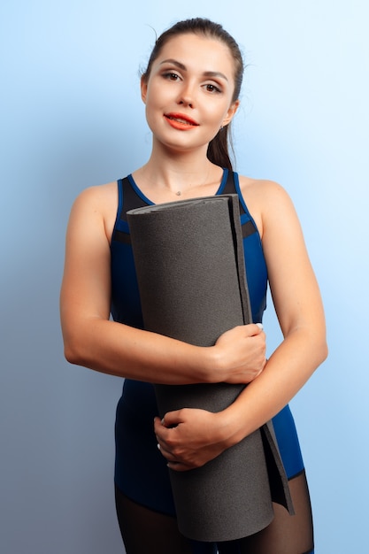 Jeune femme mince, tenant des tapis de yoga dans ses mains