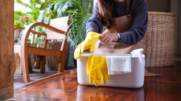 Une jeune femme a mis des gants de protection avant de nettoyer la maison