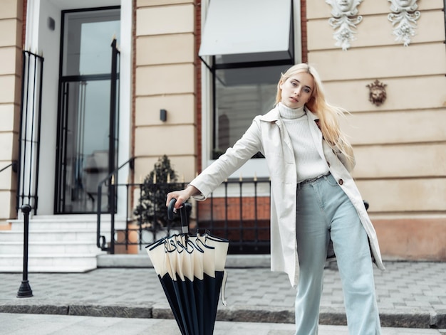 Jeune femme de mode avec un bâton de marche parapluie dans la ville