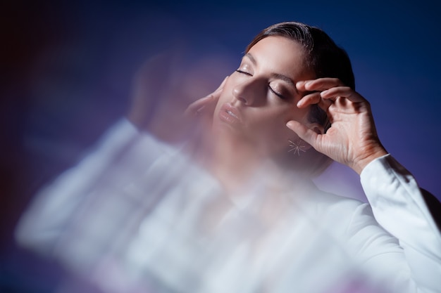 Jeune femme à la mode élégante dans le portrait dynamique blanc par des facettes en cristal