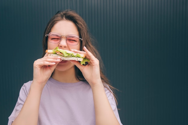 Jeune femme à la mode élégante mordre un morceau de sandwich et savourer un repas