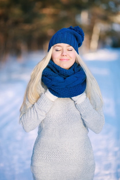 Jeune femme à la mode portant une écharpe bleue chaude, un bonnet et un pull