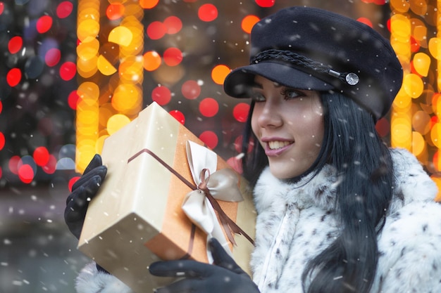 Jeune femme à la mode recevant un cadeau à la foire des vacances pendant les chutes de neige. Espace libre