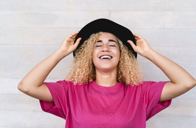 Jeune femme à la mode souriant en plein air tout en portant un chapeau élégant - Focus sur le visage