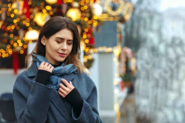 Jeune femme à la mode vêtue d'un manteau tendance marchant dans la rue en hiver. Espace libre