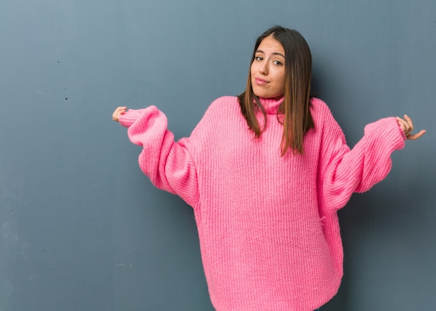 Jeune femme moderne doutant et haussant les épaules