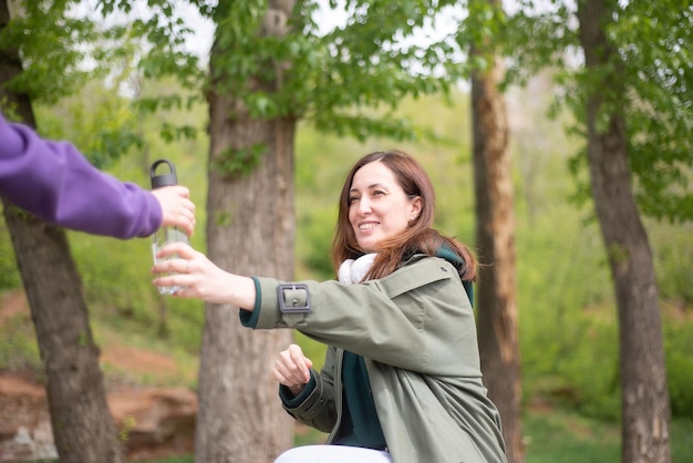 Une jeune femme moderne tend une bouteille d'eau à son fils