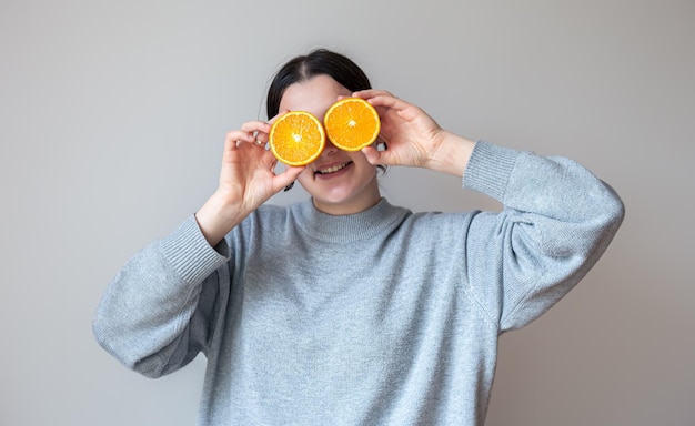 Une jeune femme avec des moitiés appétissantes d'une orange sur fond blanc