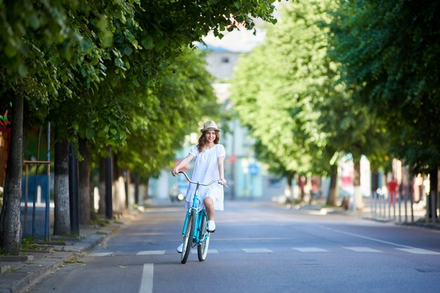 Jeune femme monte sur la route sur un vélo rétro un jour d'été