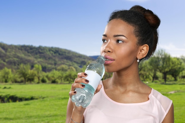 Jeune femme montrant une bouteille d'eau