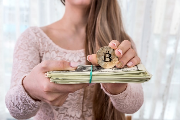 Jeune femme montrant un paquet de dollars et de bitcoin doré