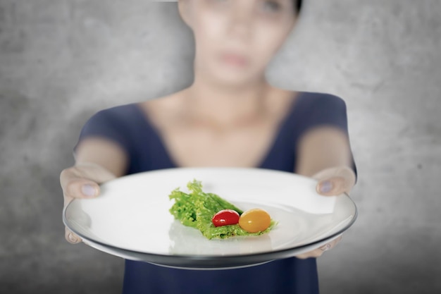 Jeune femme montrant une petite portion de salade