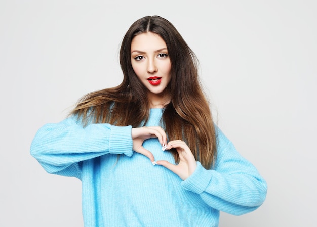 Jeune femme montrant avec son doigt la figure du coeur envoyant de l'amour à son amant