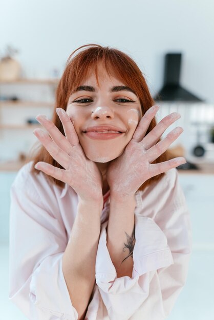 Jeune femme montre ses mains dans la farine dans la cuisine