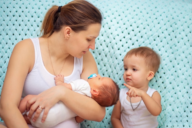 Une jeune femme montre à son fils aîné son jeune frère nouveau-né