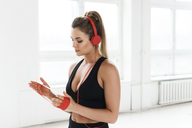 Jeune femme motivée écoutant de la musique pendant son entraînement avec une bande de résistance en boucle